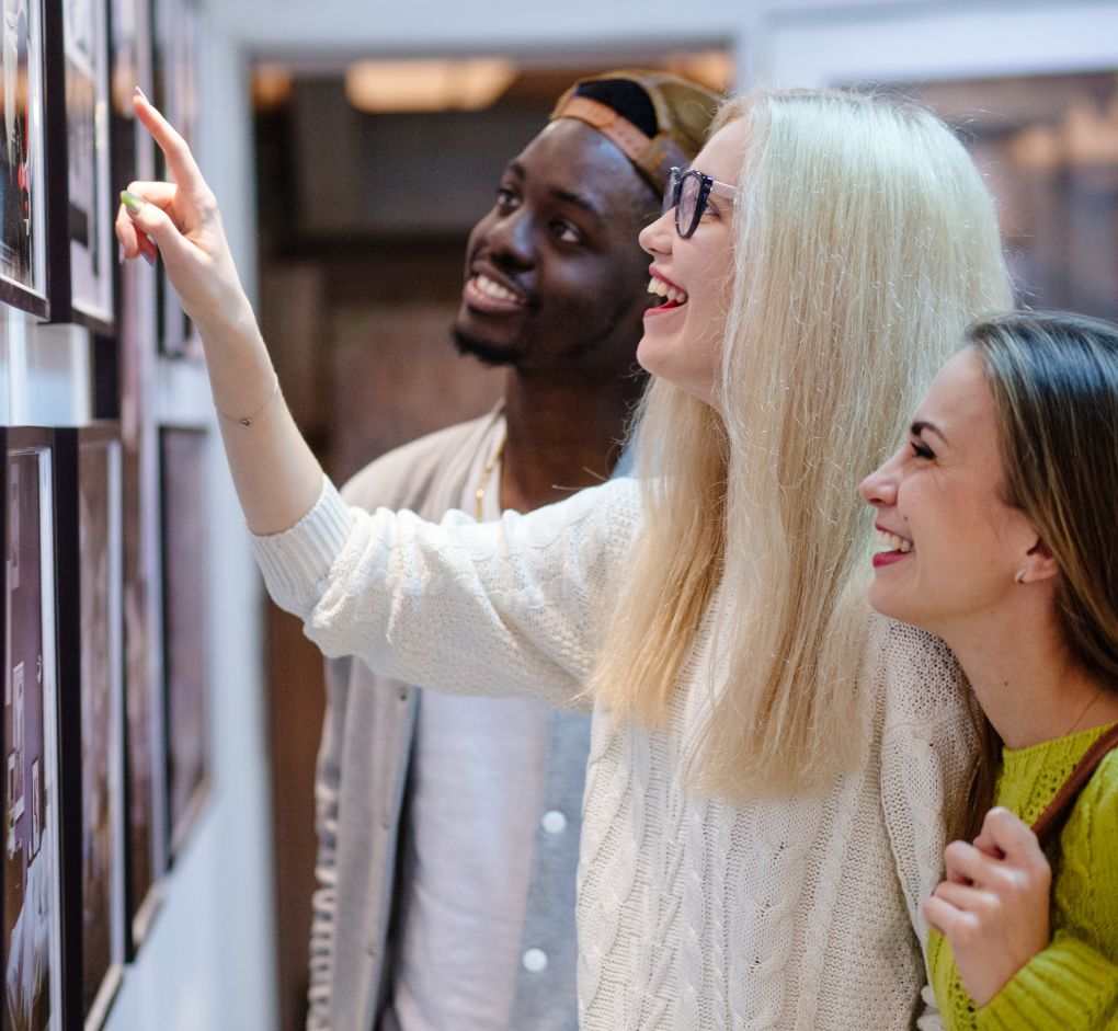 friends smiling at photos on wall